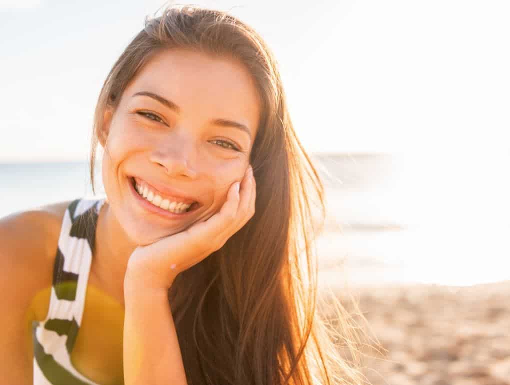 young dark haired woman on beach smiling and happy