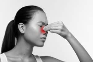unhappy japanese woman with closed eyes rubbing red sore nose suffering from rhinitis