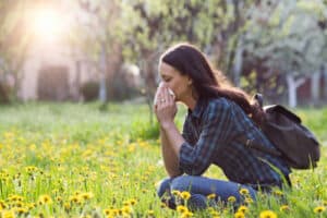 woman blowing nose in grassland with spring flowers