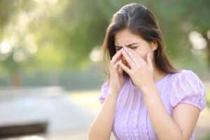A woman rubbing her eyes outdoors because of spring allergies